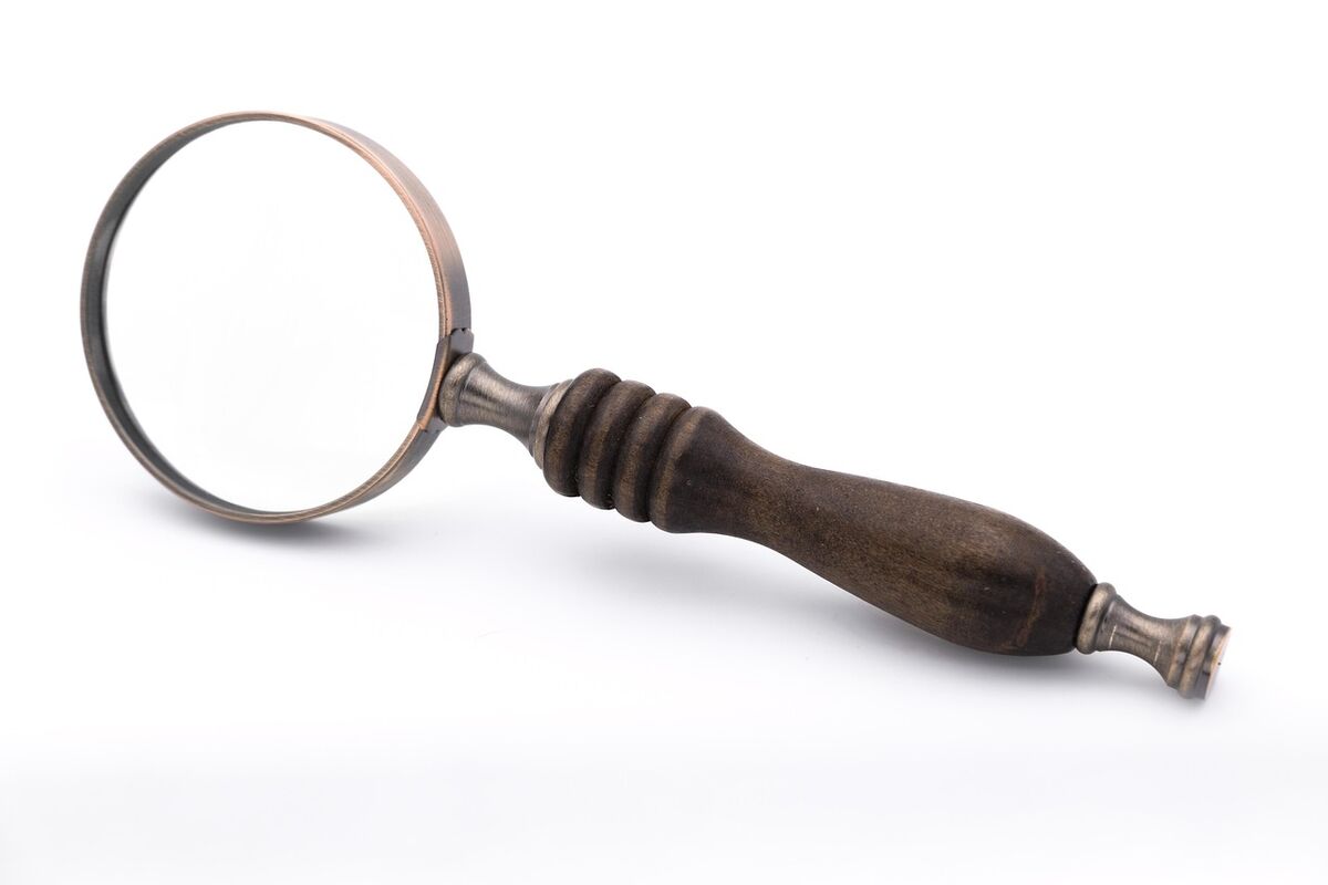 A magnifying glass held over a small model house